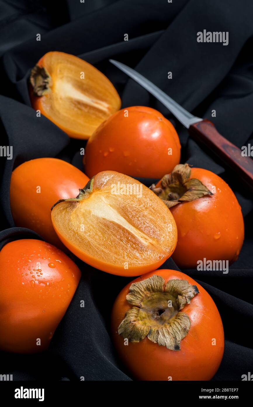 Fresh ripe persimmon fruit, winter fruit, cut on board and black background Stock Photo