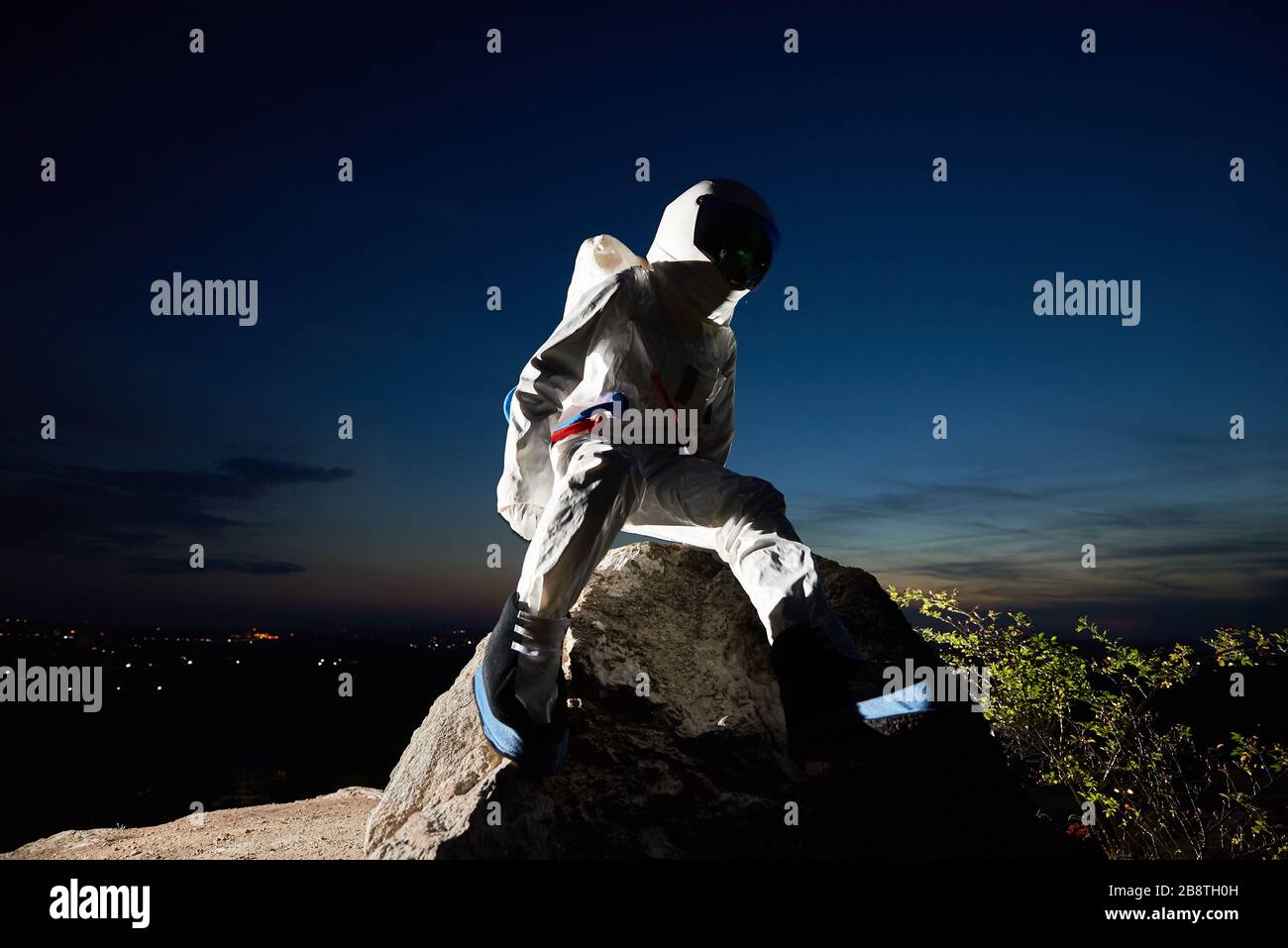 Premium Photo  A spaceman sits on a rock with a planet in the background.