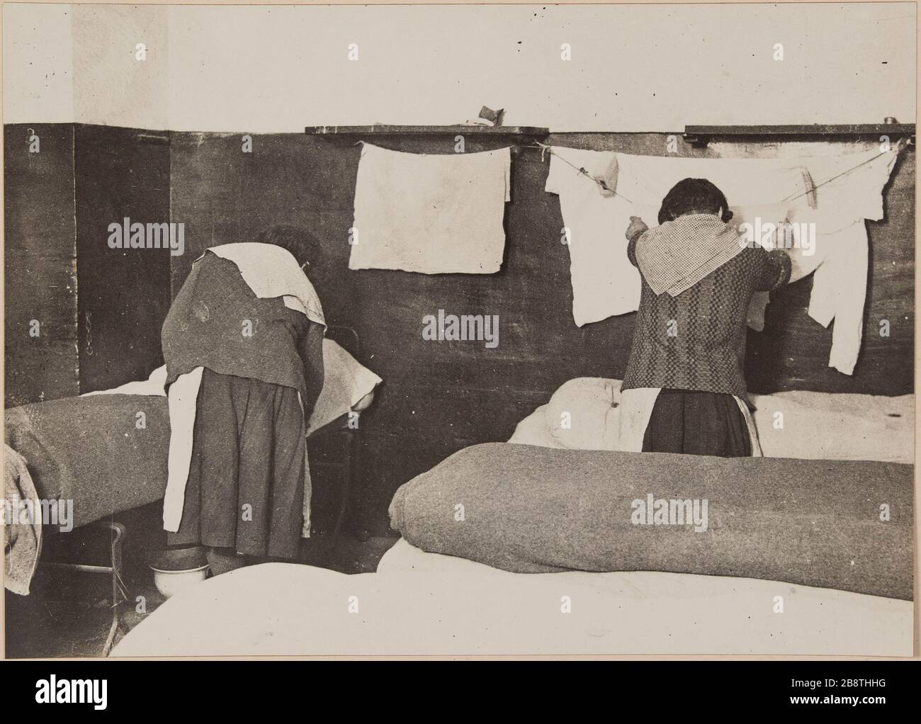 Two inmates' female chores 'extending the machine in a cell, jail Saint Lazare prison for women, 107 rue du Faubourg Saint-Denis, 10th arrondissement, Paris. Deux détenues 'femmes de corvées' étendant du linge dans une cellule, prison Saint-Lazare, maison d’arrêt pour femme,107 rue du Faubourg-Saint-Denis. Paris (Xème arr.). Photographie d'Henri Manuel (1874-1947). Tirage gélatino-argentiques au bromure sur papier, collé sur un page d'album cartonnée. Agrandissement d’après une plaque négative sur verre. 1929-1931. Paris, musée Carnavalet. Stock Photo