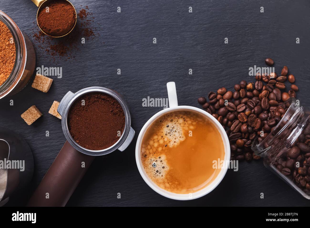 Black coffee, filter holder of espresso maker and scattered roasted coffee beans Stock Photo