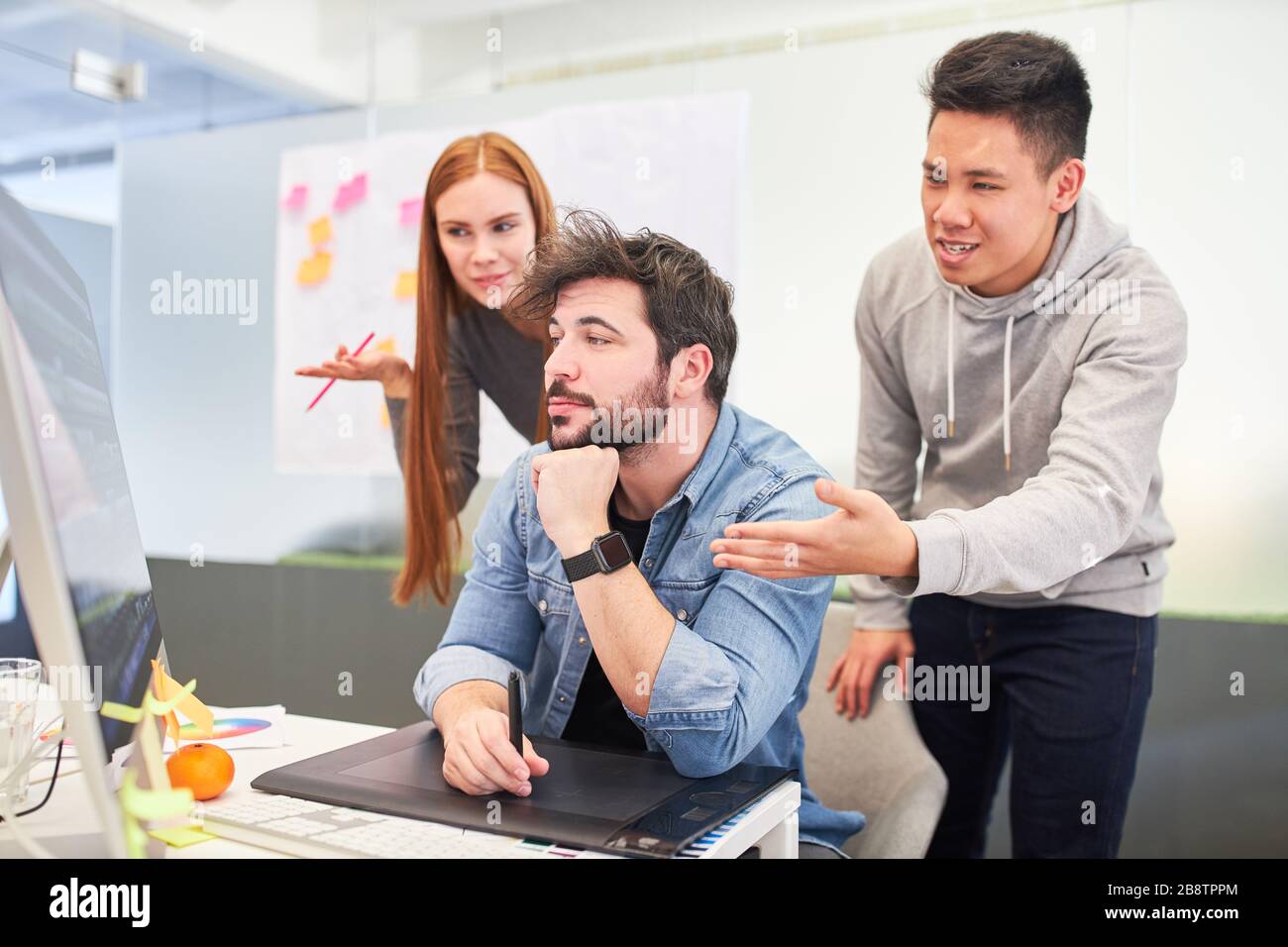 Web designers and graphic designers on the computer discuss a creative solution Stock Photo