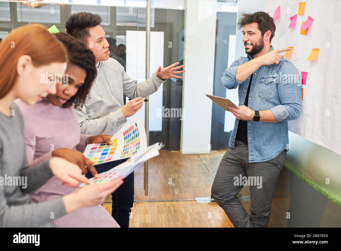 Graphic designers and web developers discuss a design project during brainstorming Stock Photo