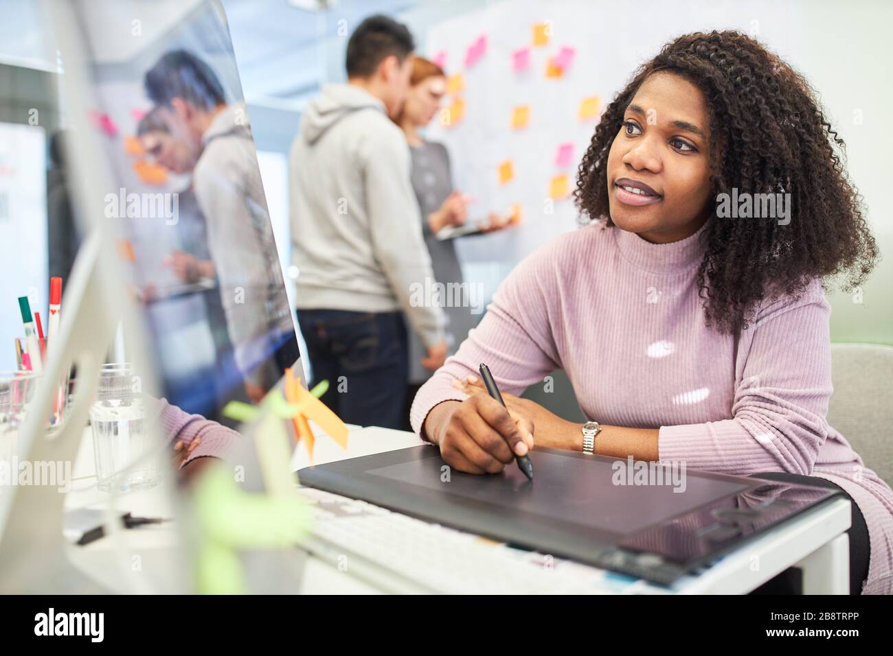 African woman as a graphic designer uses the pen to design a layout on a tablet computer Stock Photo