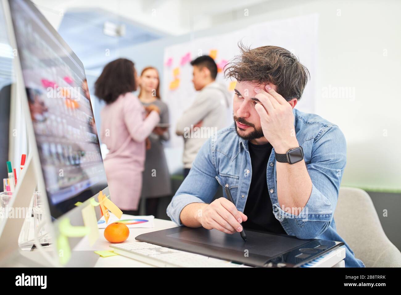 Web designer or web developer sits exhausted on the computer in the internet agency Stock Photo