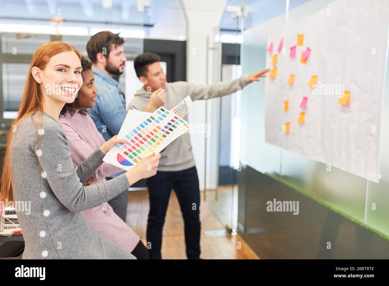Young business woman with her creative team brainstorming with sticky notes Stock Photo