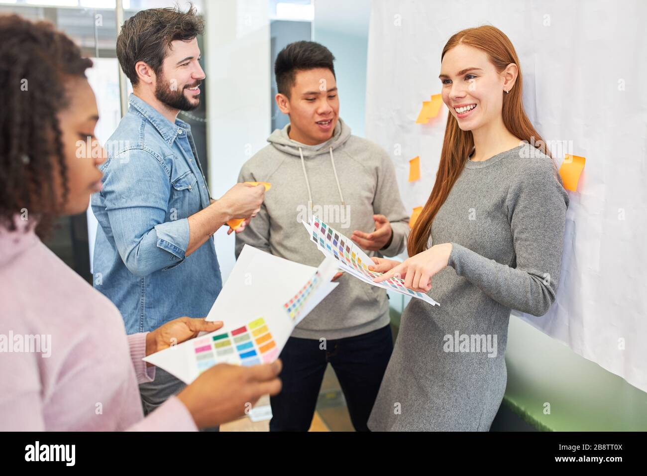 Graphic designers and developers discuss color design of a website in a meeting Stock Photo