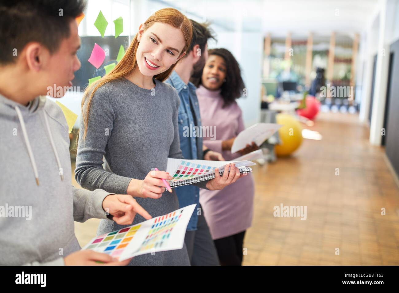 Young graphic designers discuss color choices for a customer project in the workshop Stock Photo
