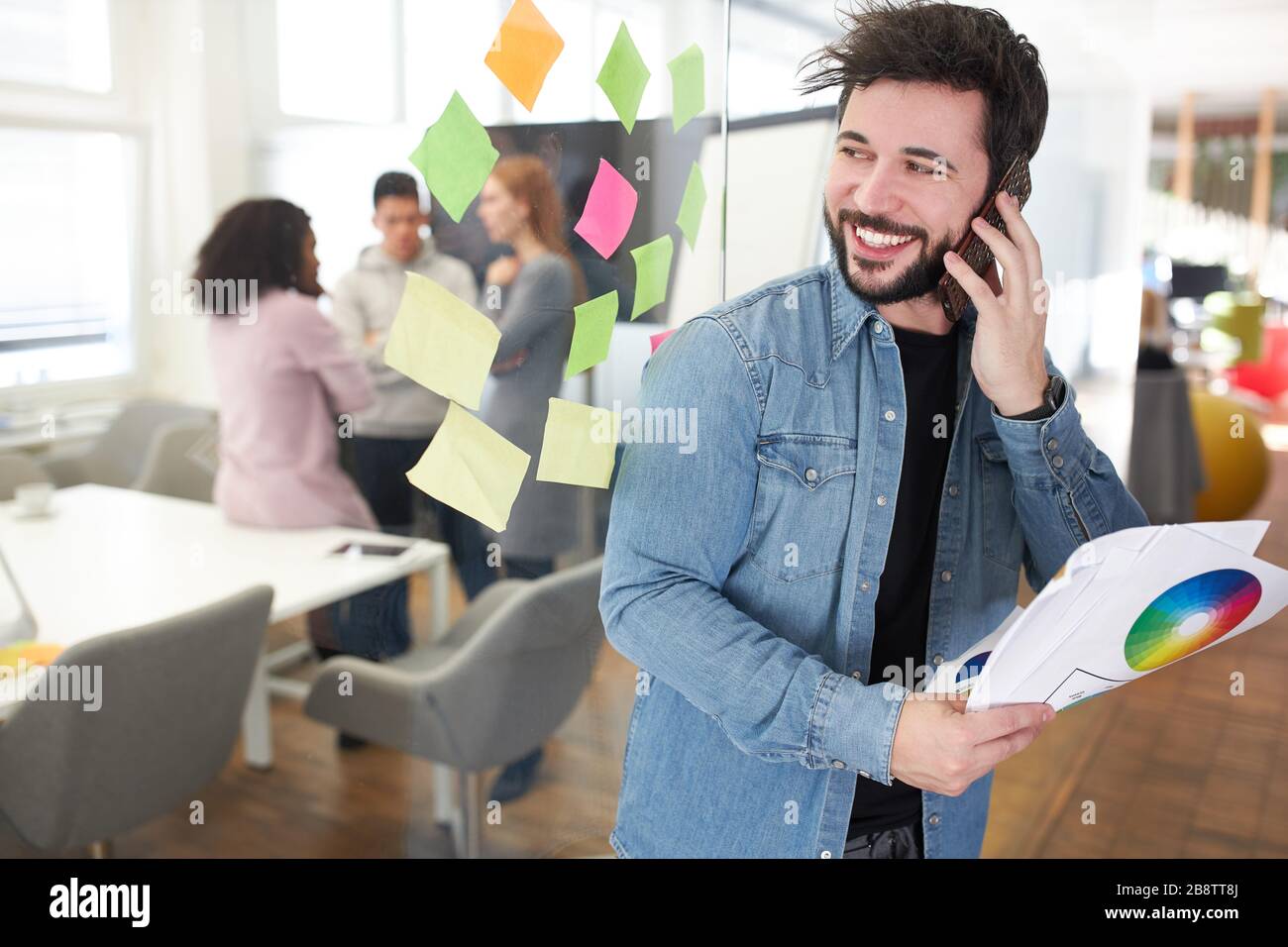 Web designer as a start-up founder calls on the smartphone in the web agency Stock Photo