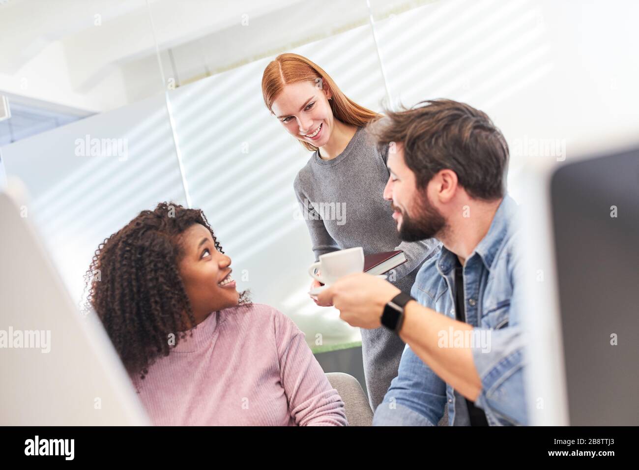 Young web designer team has a coffee break on the computer in the office Stock Photo