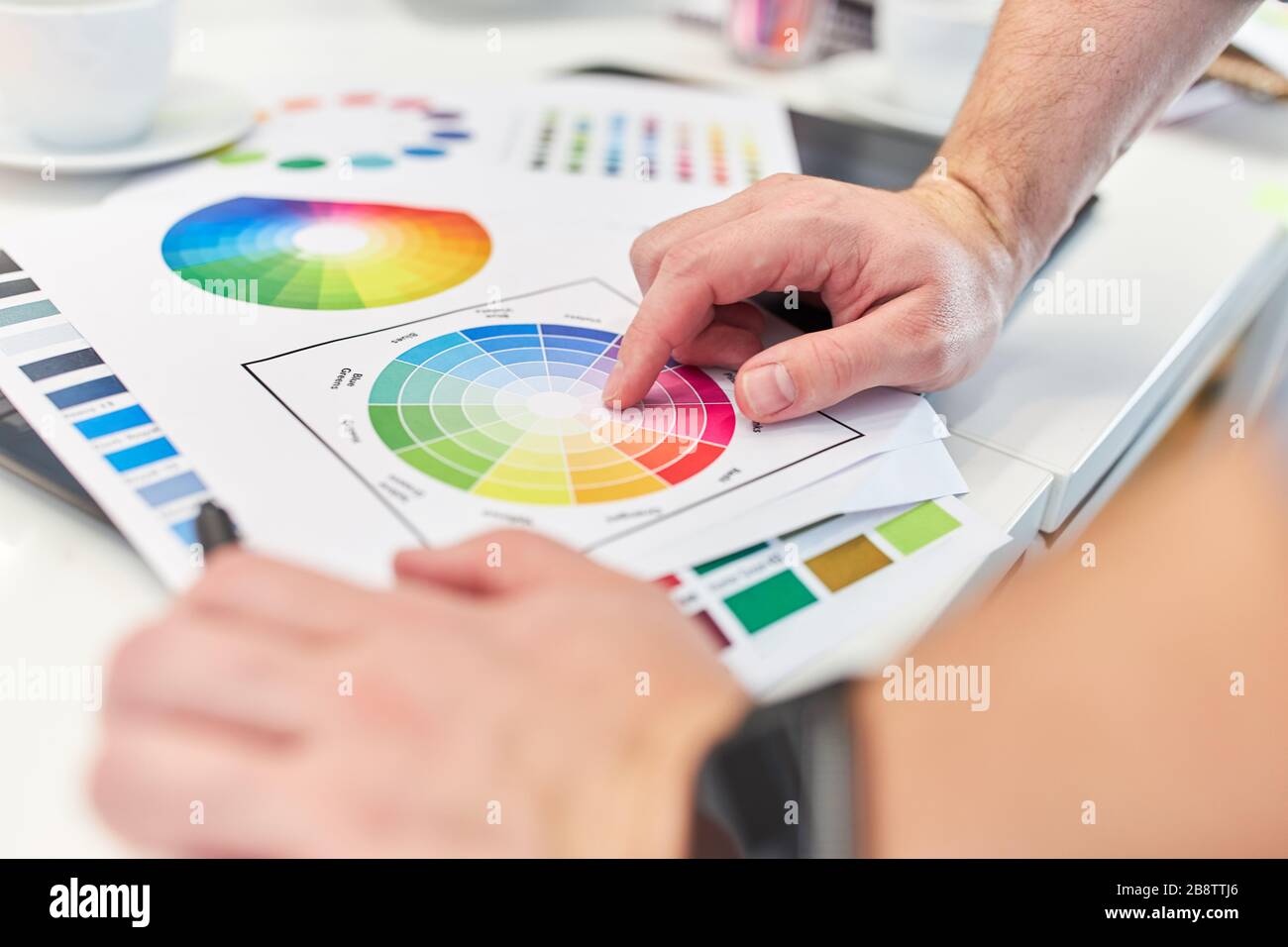 Graphic designer points to the color palette when discussing graphic design Stock Photo