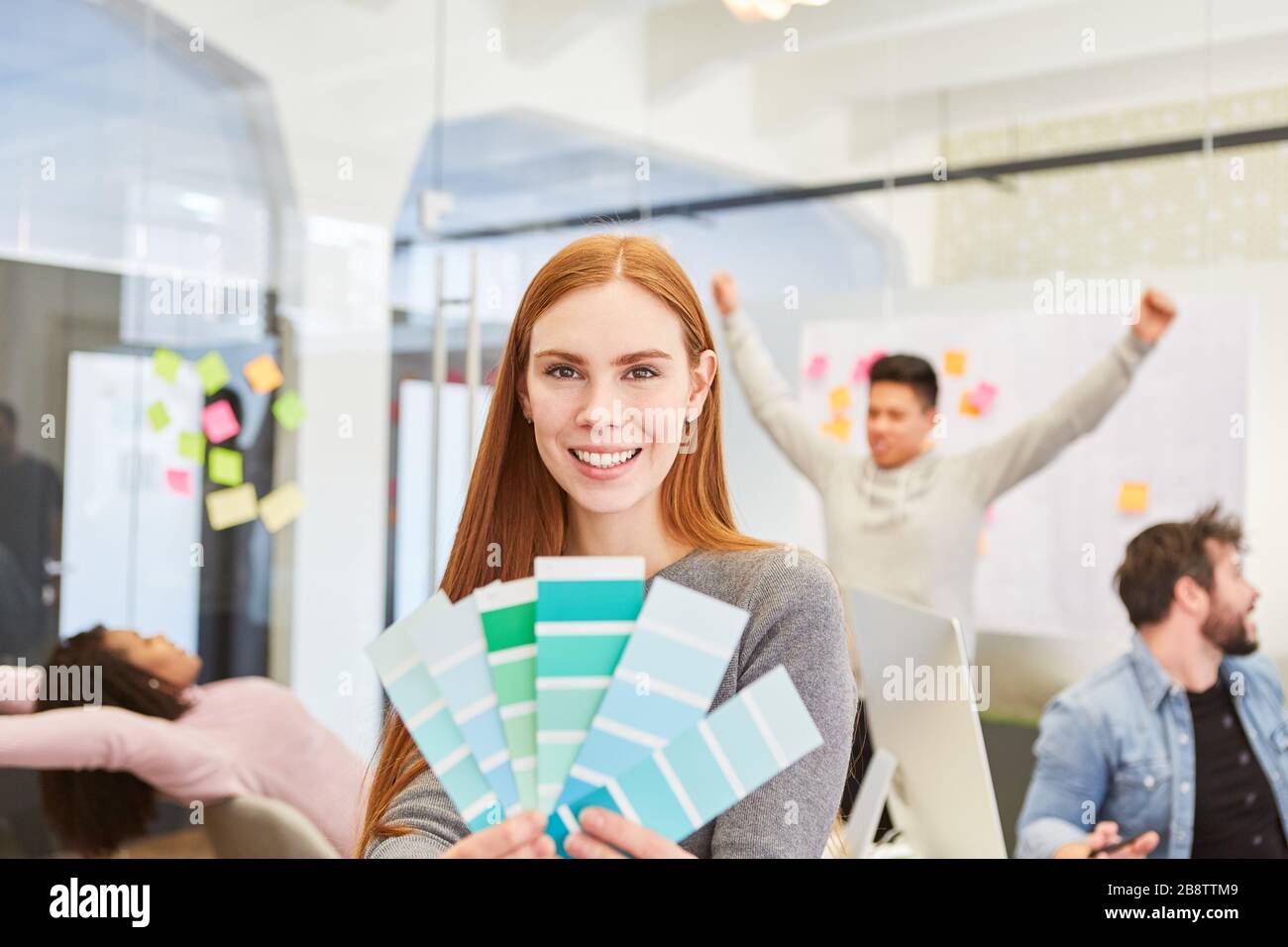 Smiling woman as a graphic designer with color palette in a meeting in the design agency Stock Photo
