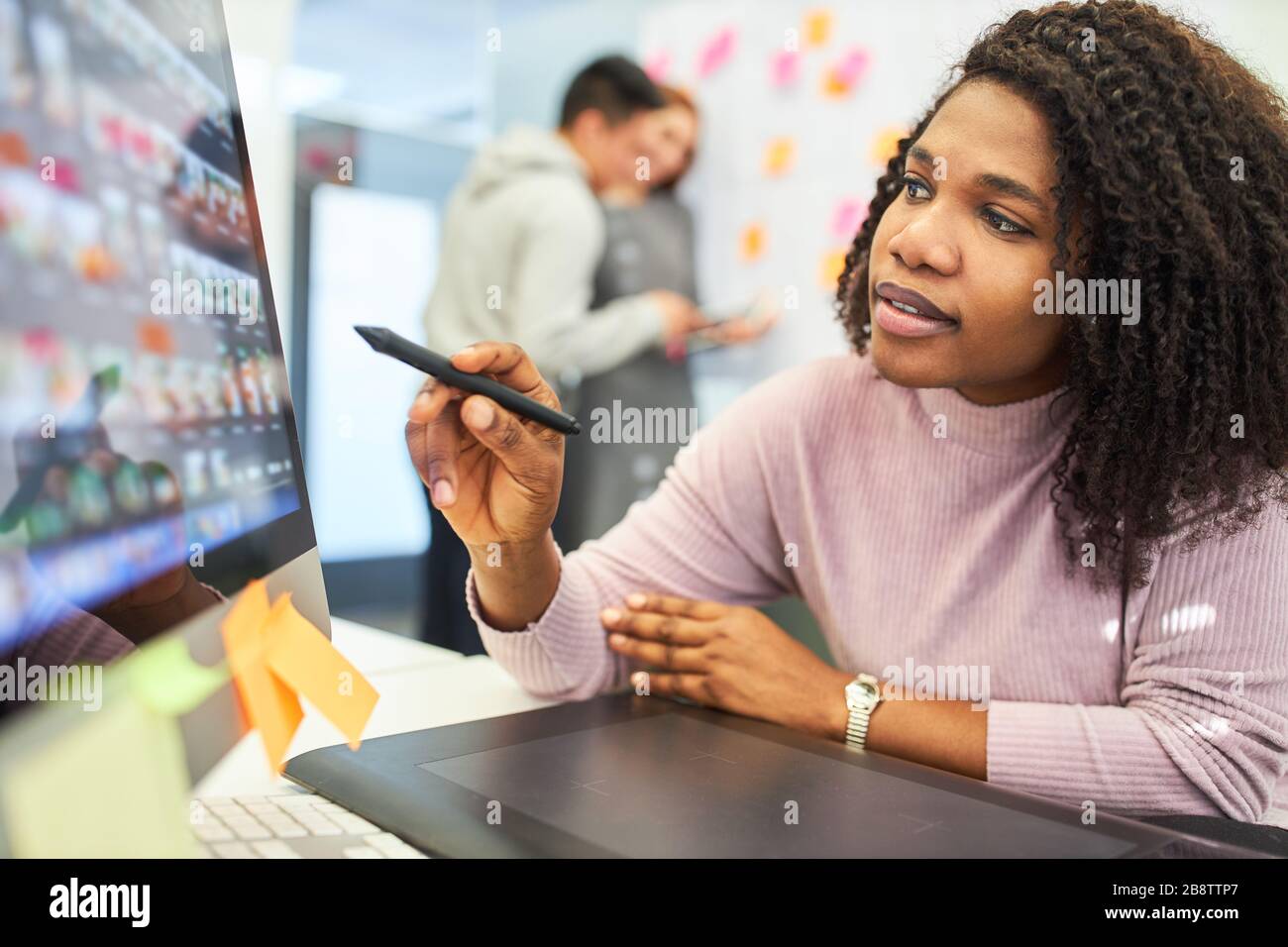 Creative African graphic designer with pen pointing at the computer monitor Stock Photo