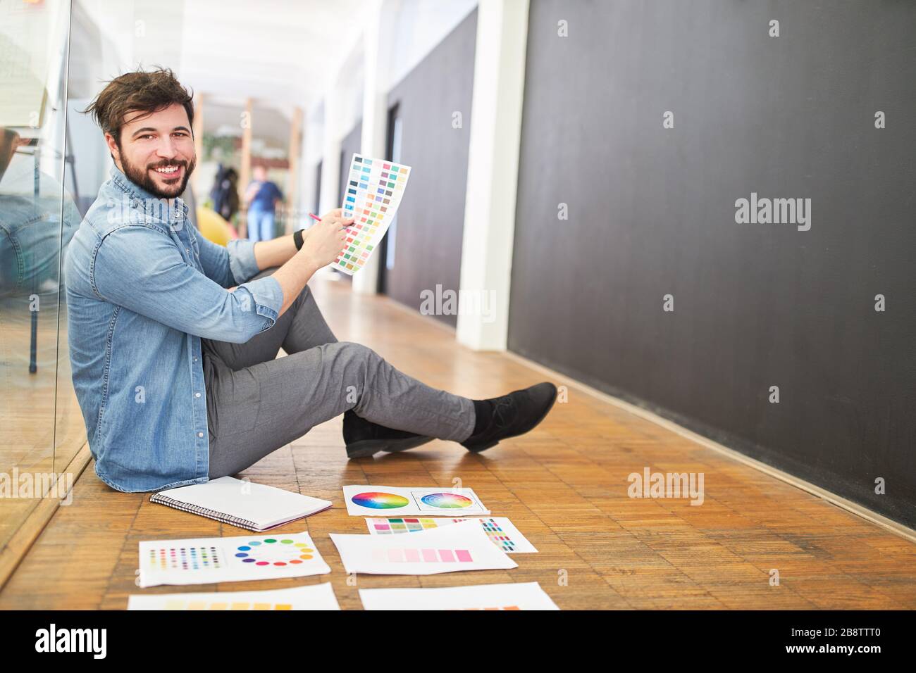 Satisfied graphic designer in the color selection with color palette in the design agency Stock Photo