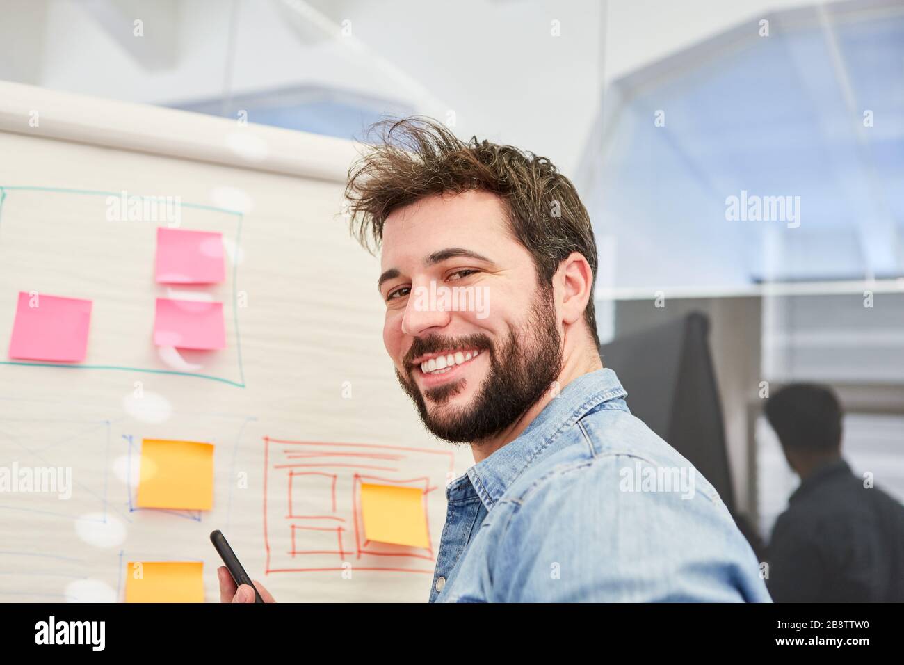 Self-confident founder in front of a flipchart with sticky notes and graphics Stock Photo