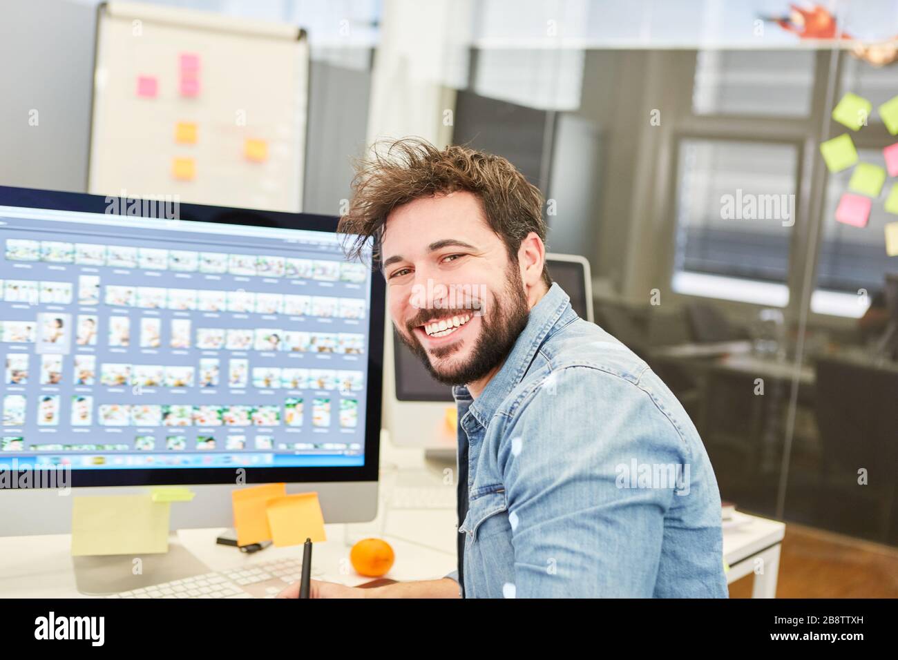 Graphic designer smiling on PC while designing a website in the design agency Stock Photo