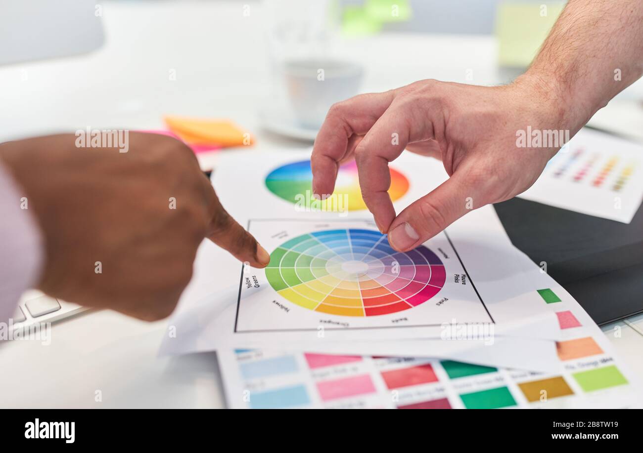 Hands of two graphic designers point to color palette while brainstorming Stock Photo