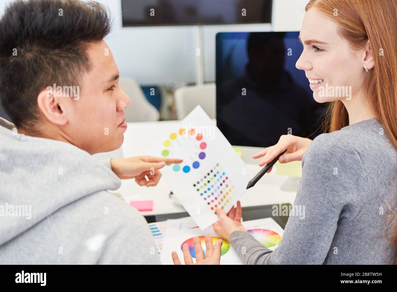 Graphic designers in the start-up team discuss an idea for the color design of a website Stock Photo