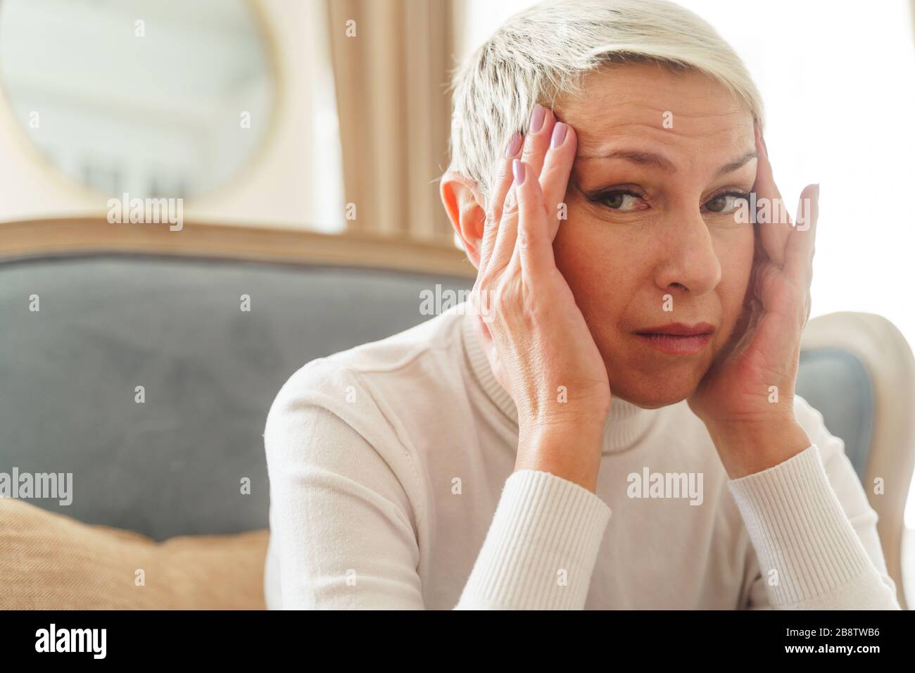 Despondent grey-haired female staring at the camera Stock Photo