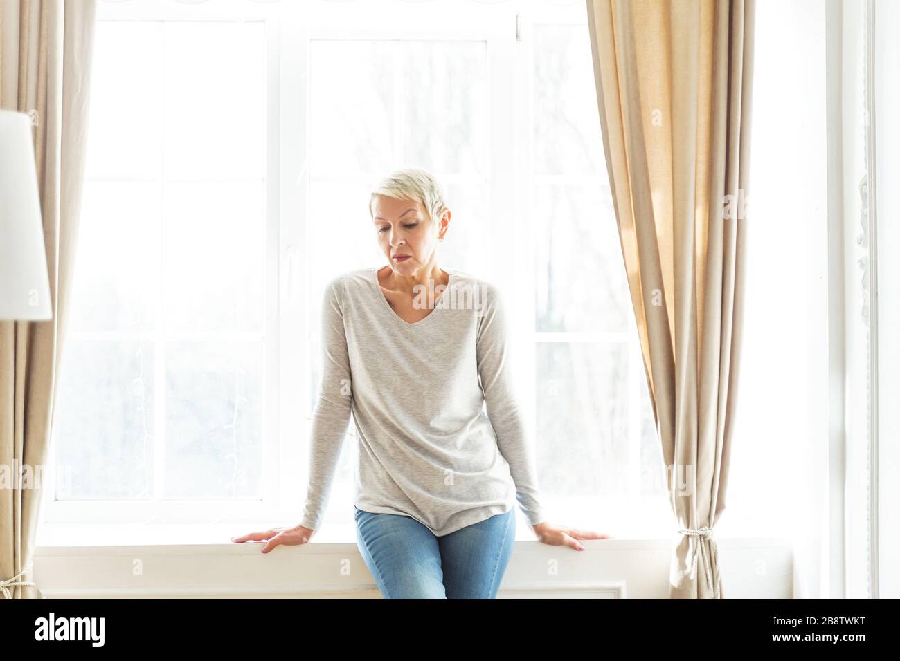Depressed grey-haired elderly Caucasian lady looking down Stock Photo