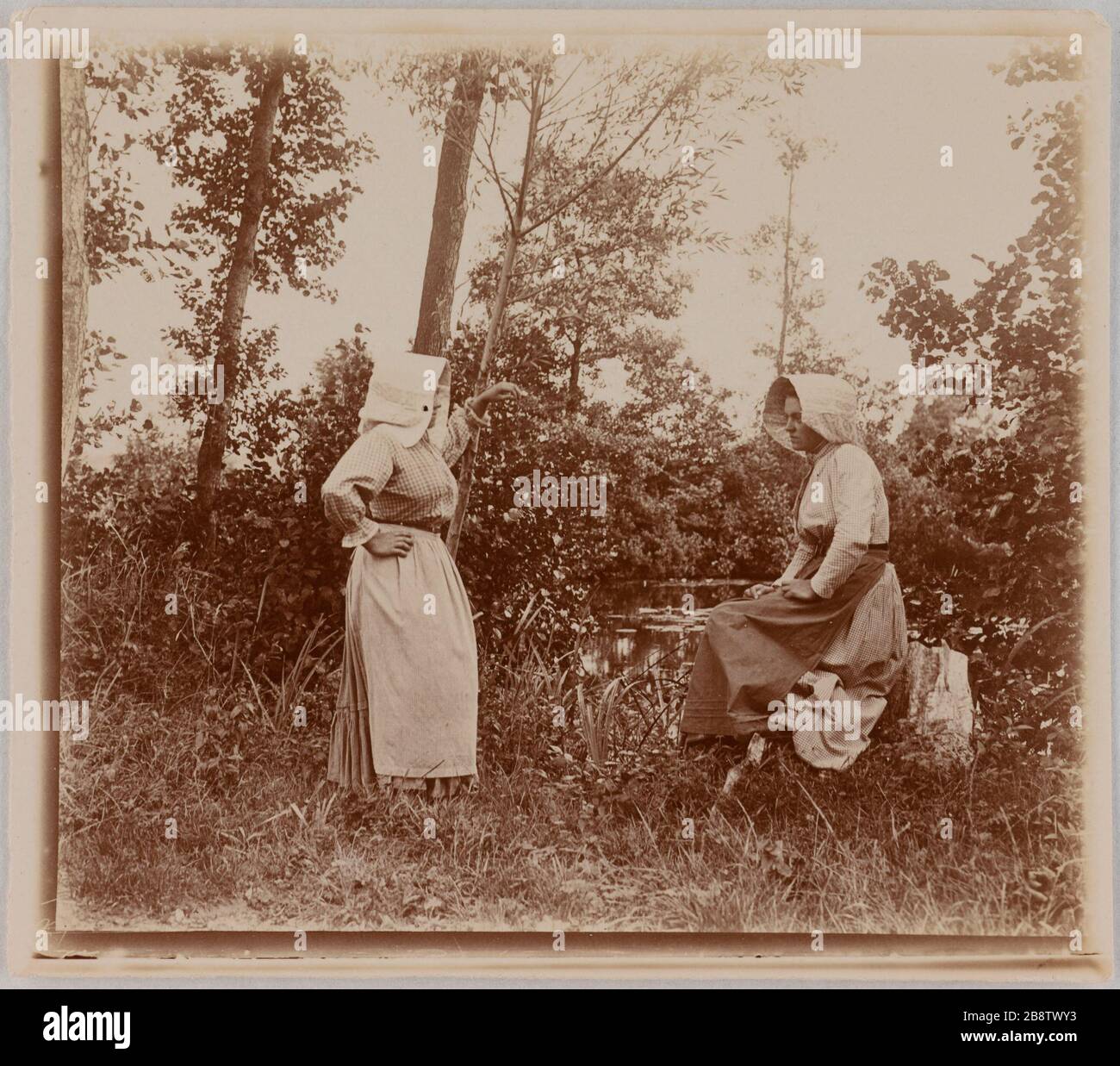Two women with a seat on a stump near a body of water, Amiens. Deux femmes dont l'une assise sur une souche près d'une étendue d'eau, Amiens. Photographie de Lagrange. Paris, musée Carnavalet. Stock Photo