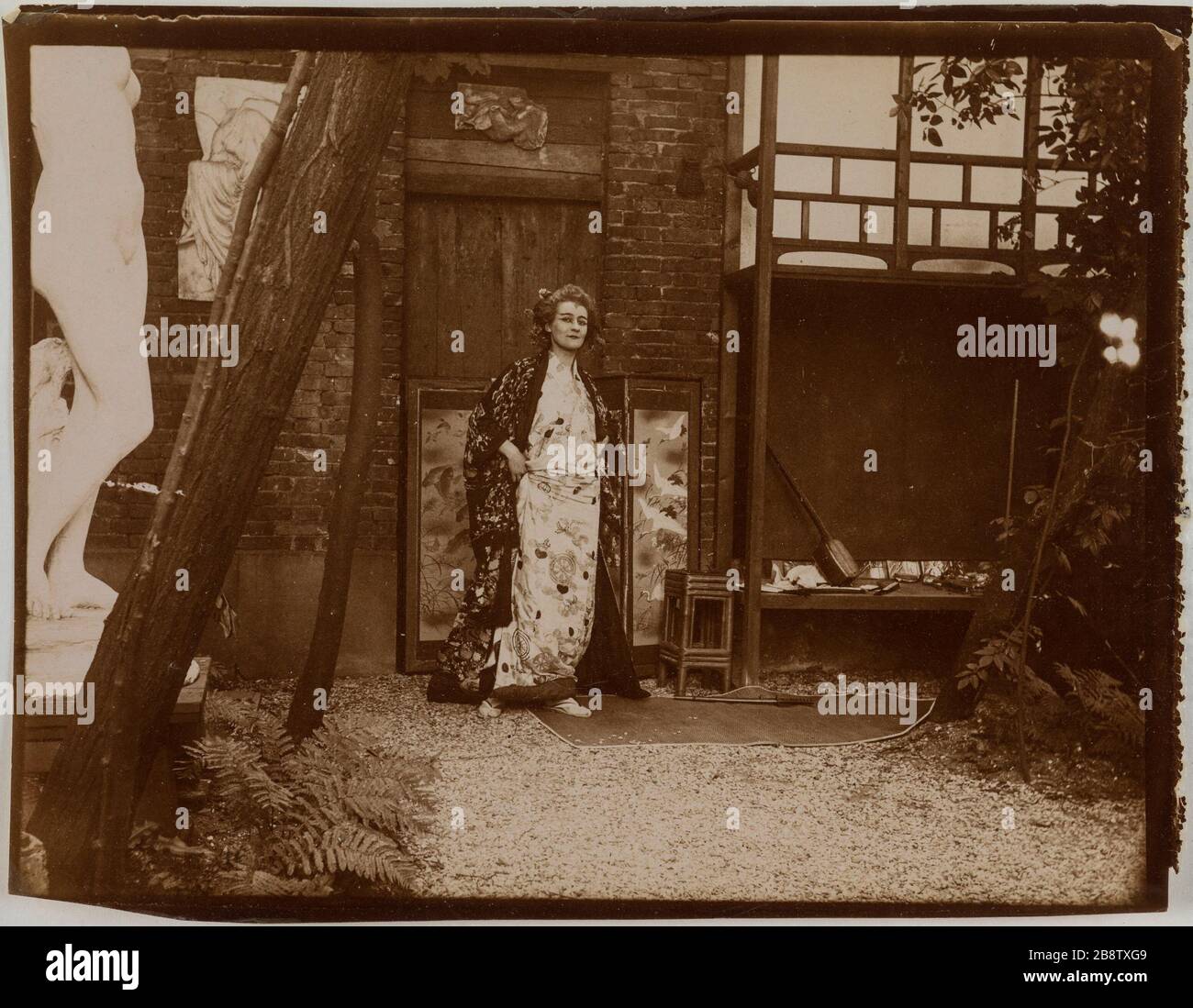 Actress in Japanese kimono posing in front of a screen in an outdoor  garden, a copy of a low relief of a Victory or Nike of Athena Nike temples  on the Acropolis