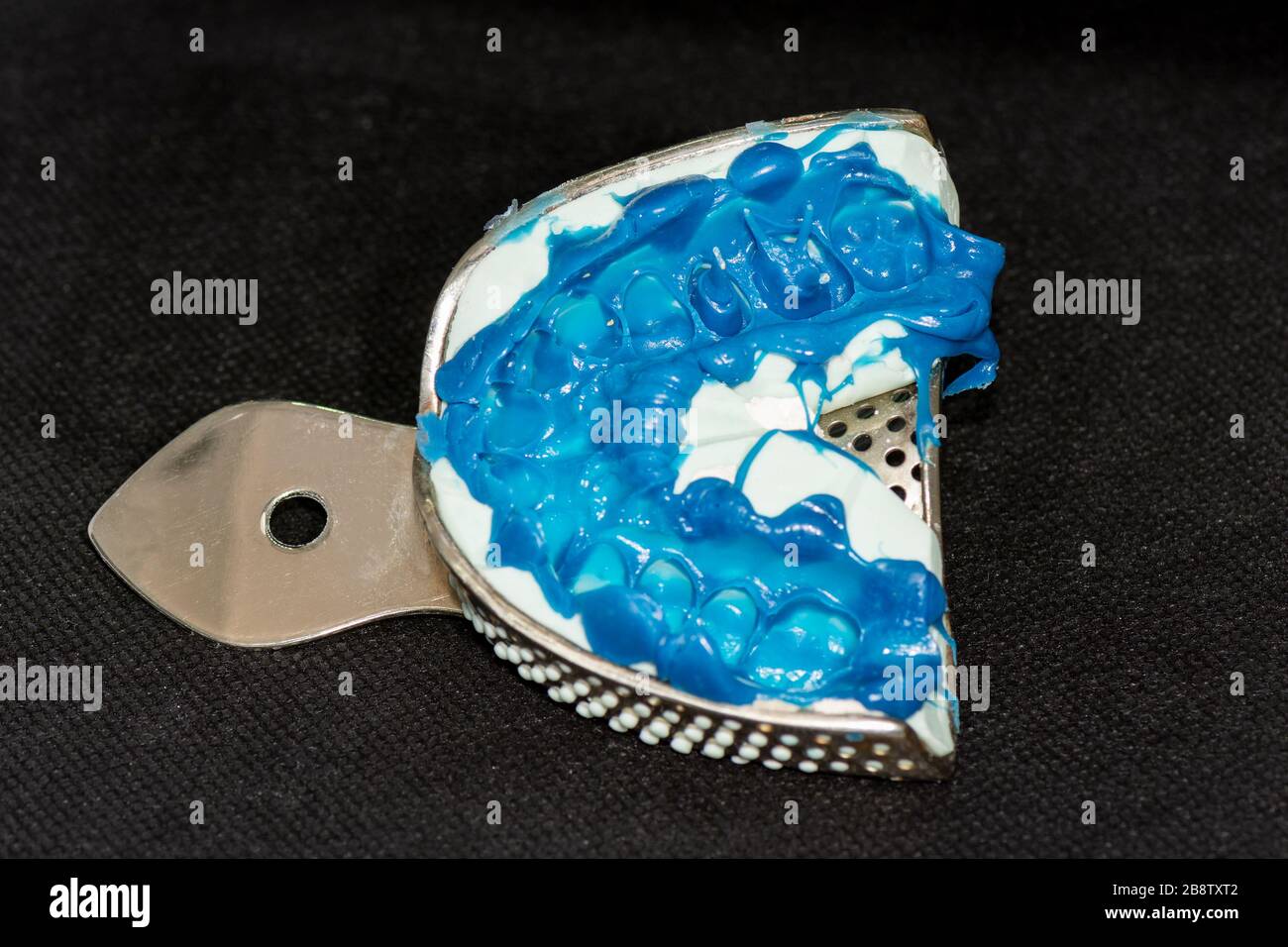 silicone tooth print for the manufacture of blue tooth pin and tooth crown. Restoration of a man’s smile in a dental clinic Stock Photo