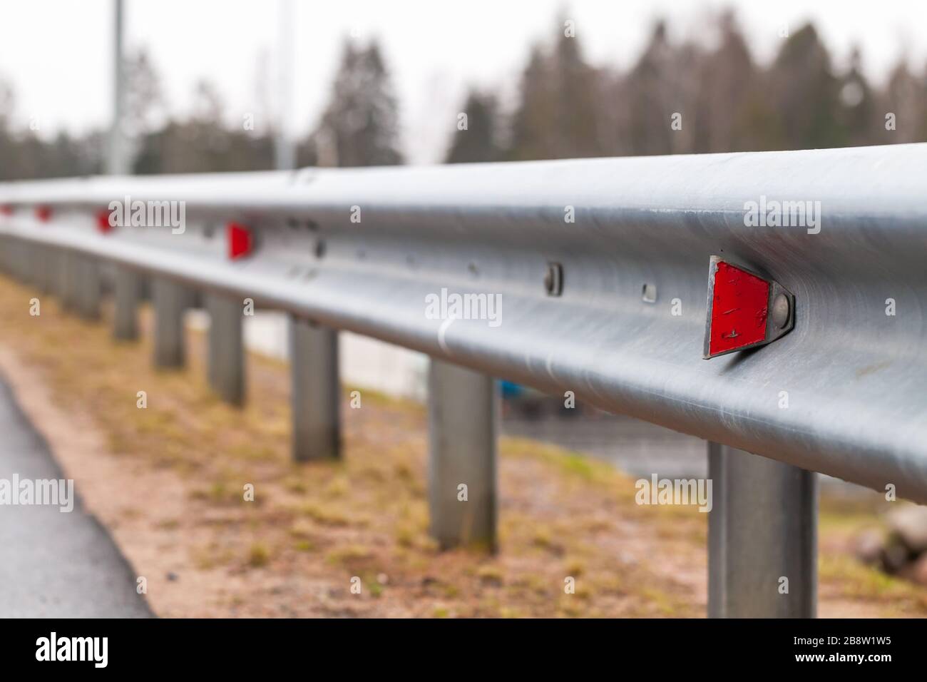 Retro-reflecting optical units are on a metal guardrail. Highway safety equipment, close-up photo with selective focus Stock Photo