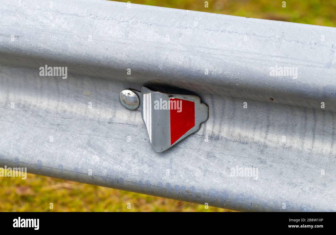 Retro-reflecting optical unit is on a metal guardrail. Highway safety equipment, close-up photo Stock Photo