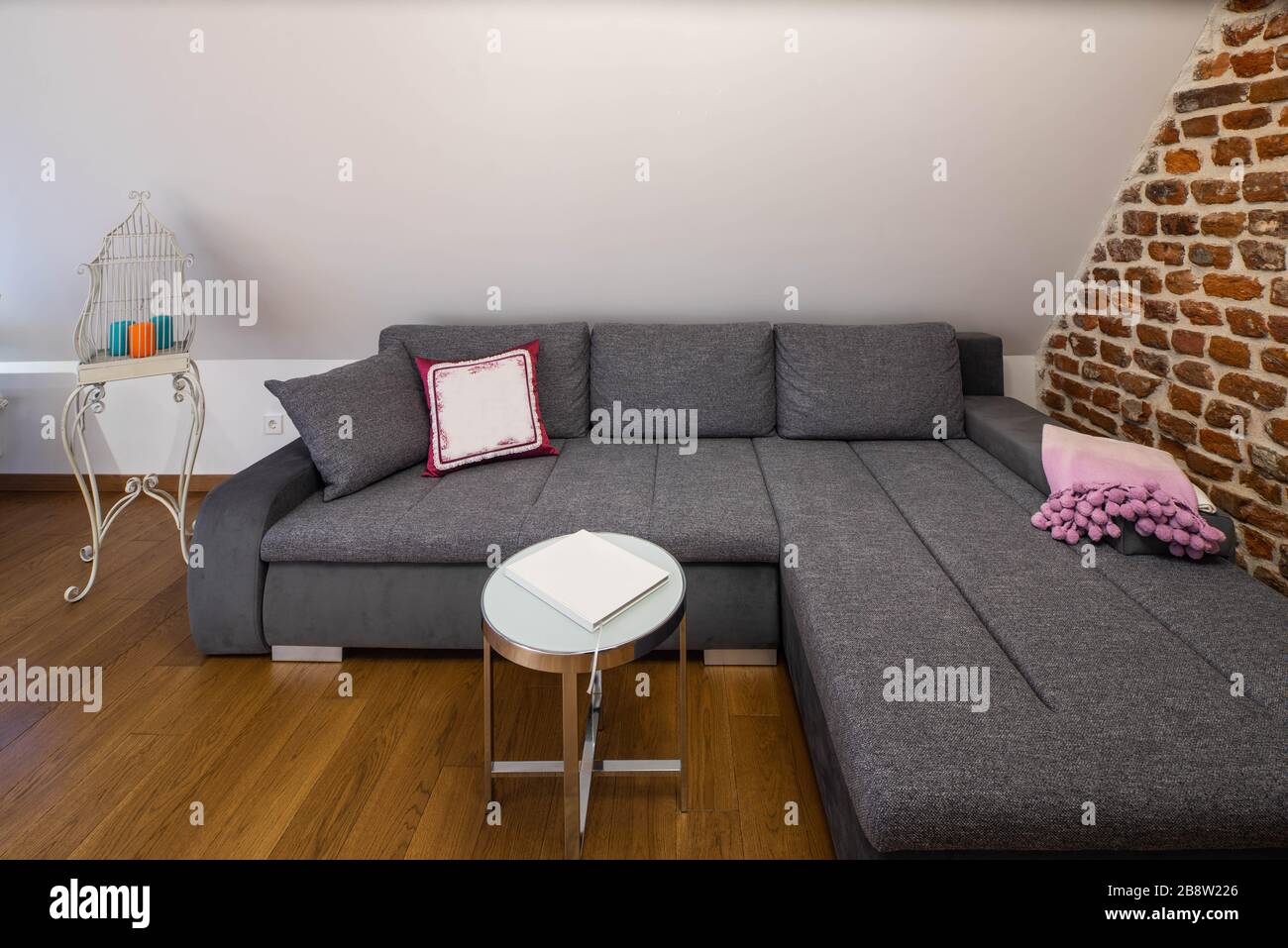 Cozy grey sofa in apartment. Modern loft interior. Coffee table. Brick