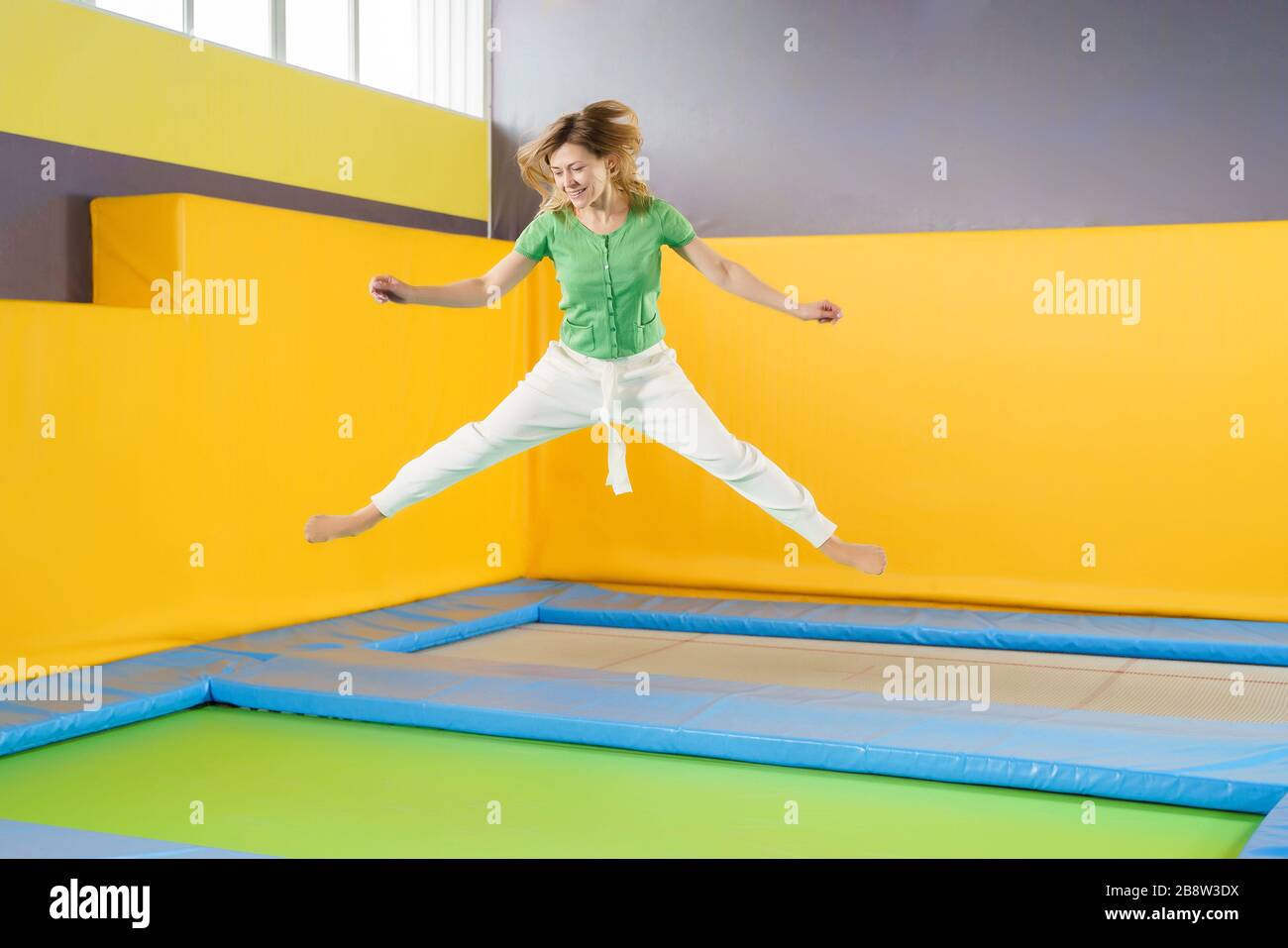 Young woman jumping and bouncing on a trampoline in sport center Stock Photo