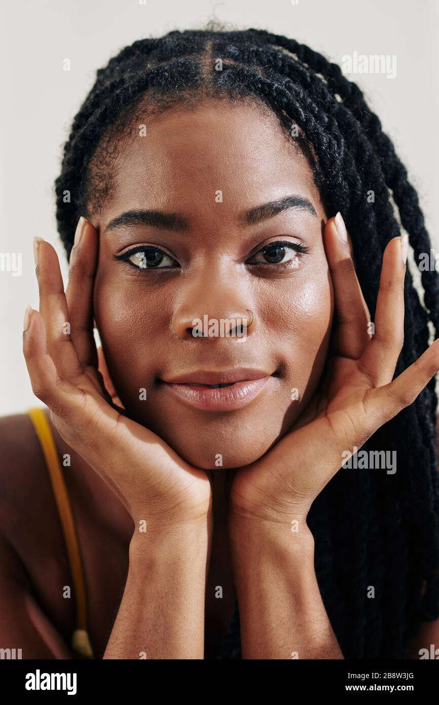 Face of beautiful young Black woman with dreadlocks looking at camera ...