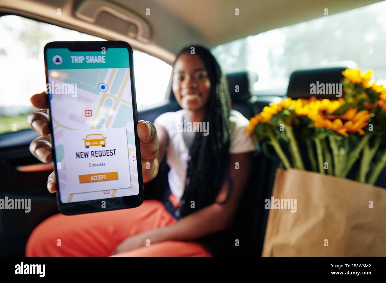 Positive woman showing car sharing app with new request notification ...