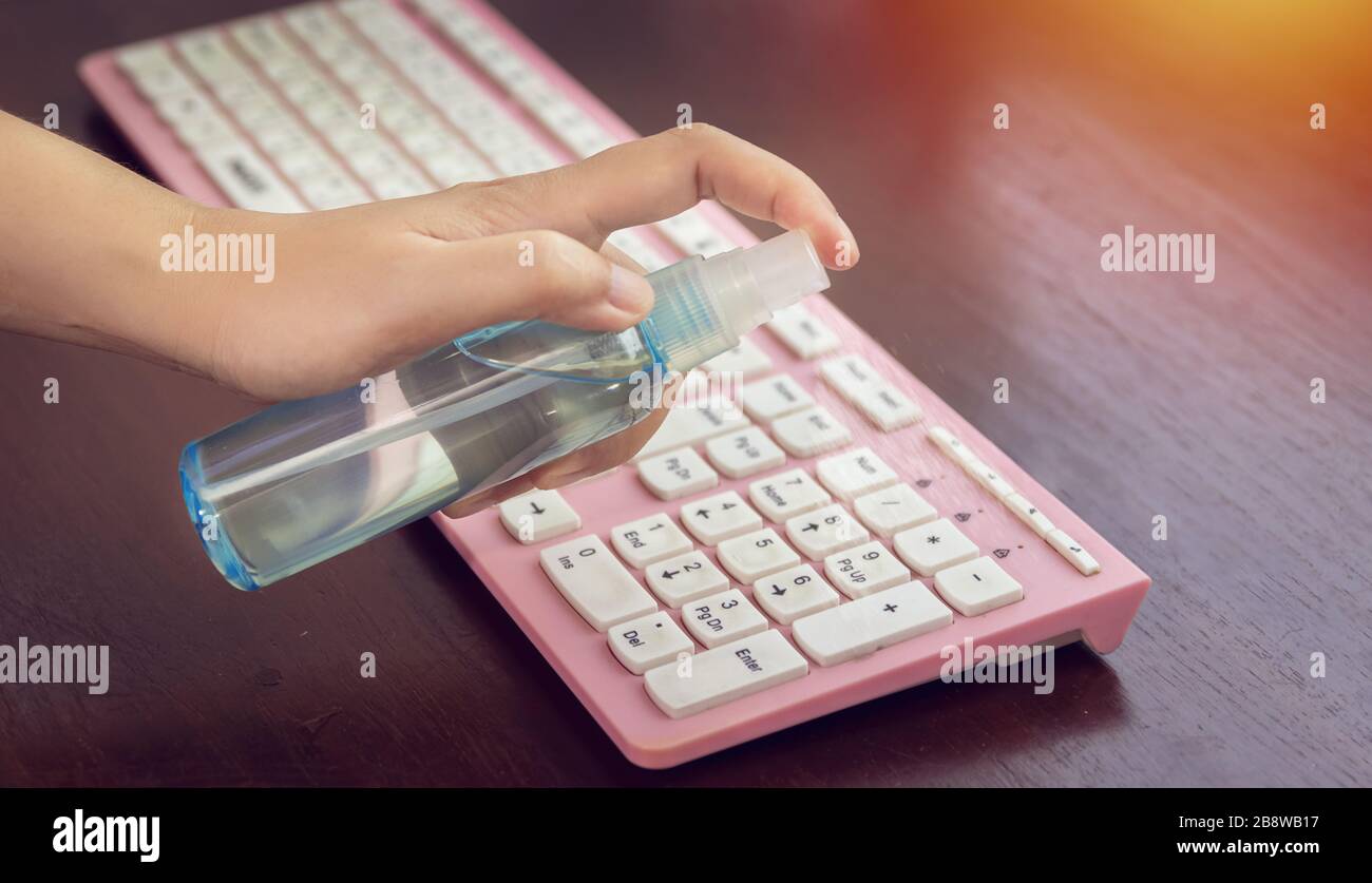 disinfect, sanitize, hygiene care. people using alcohol spray on computer keyboard and frequently touched area for cleaning and disinfection, preventi Stock Photo