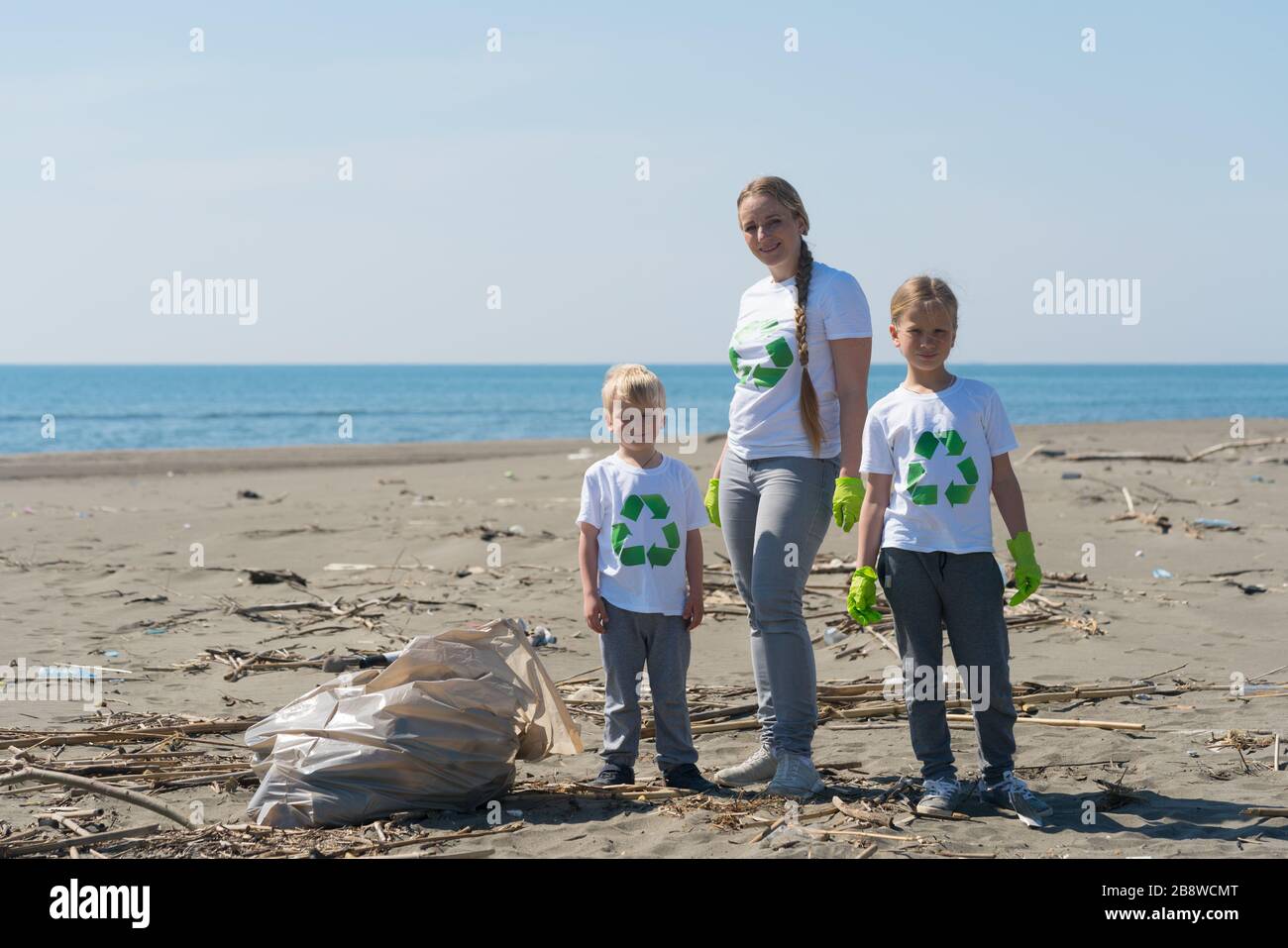 Family picks up trash from the beach in trash bags stock photo alamy