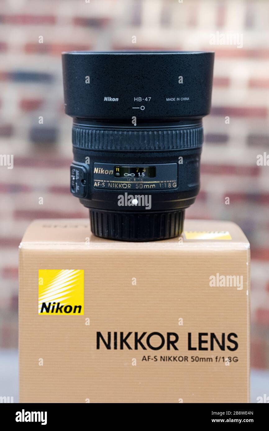 A Nikon 50mm lens with a shade on top of the box it came in. Stock Photo
