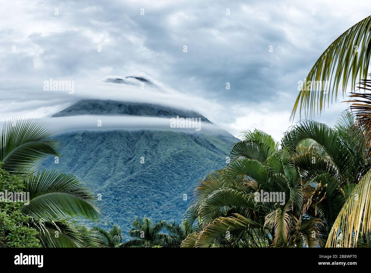 Beautiful and dramatic view of Arenal volcano surrounded by ring clouds. La Fortuna city, Costa Rica. Stock Photo