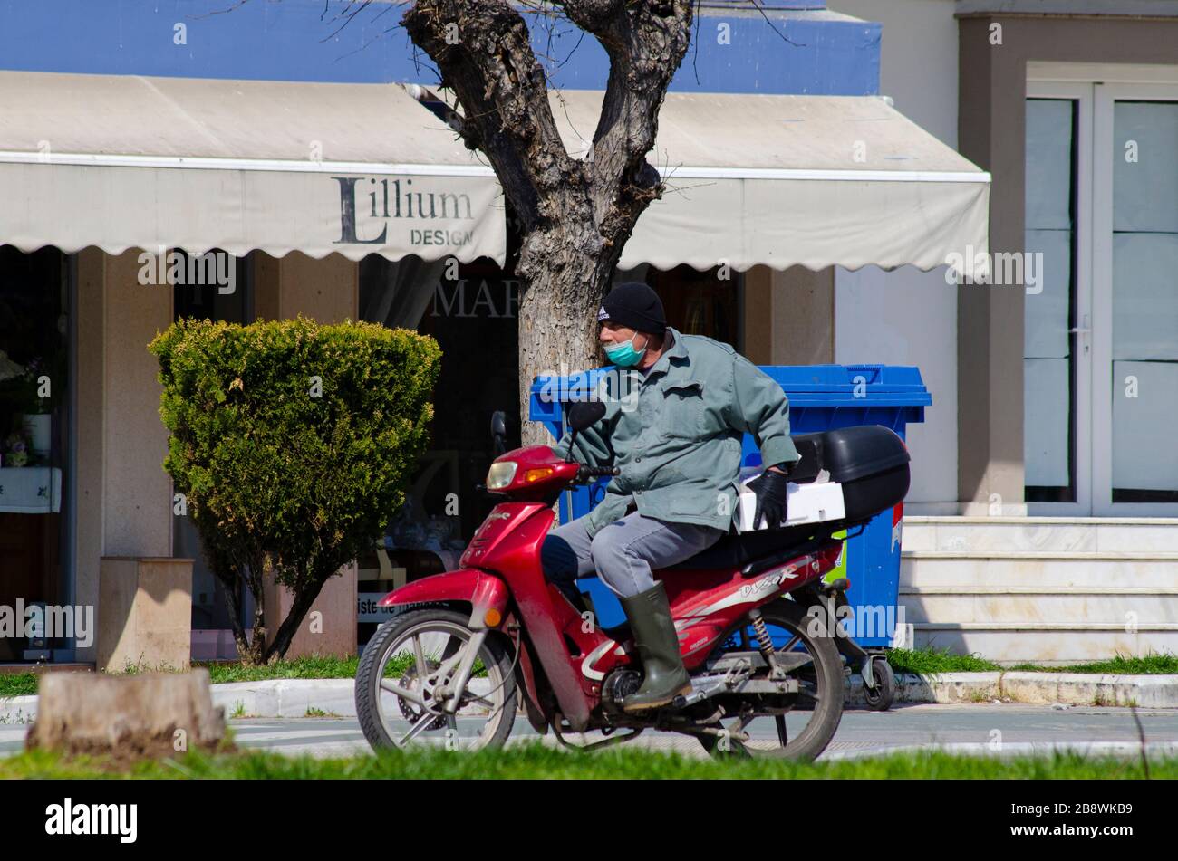 ALEXANDROUPOLI, GREECE - 21 Mar 2020 - A man on a scooter wears rubber gloves and a facemask in central Alexandroupoli, Greece, to try and protect him Stock Photo