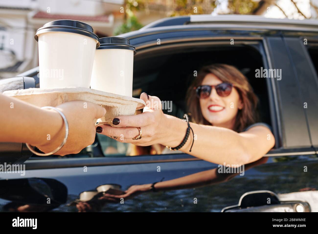 Waiter giving disposable tray with two cups of take out coffee to