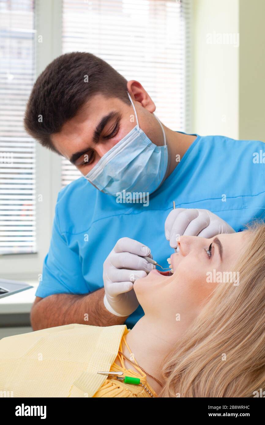 Dentist examining patient's teeth, wearing blue uniform and gloves ...