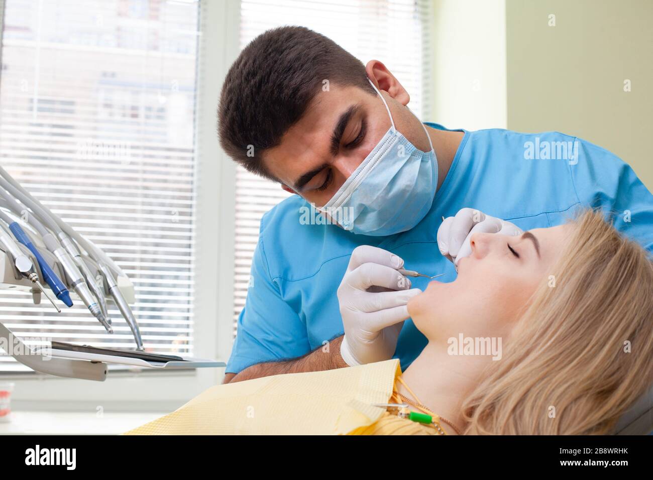 Dentist examining patient's teeth, wearing blue uniform and gloves ...