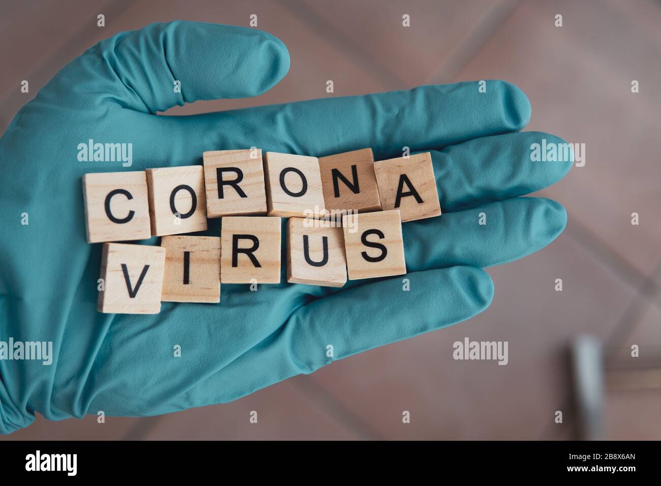 a hand with a glove on holds Scrabble bricks, which form the word: Corona Virus Stock Photo