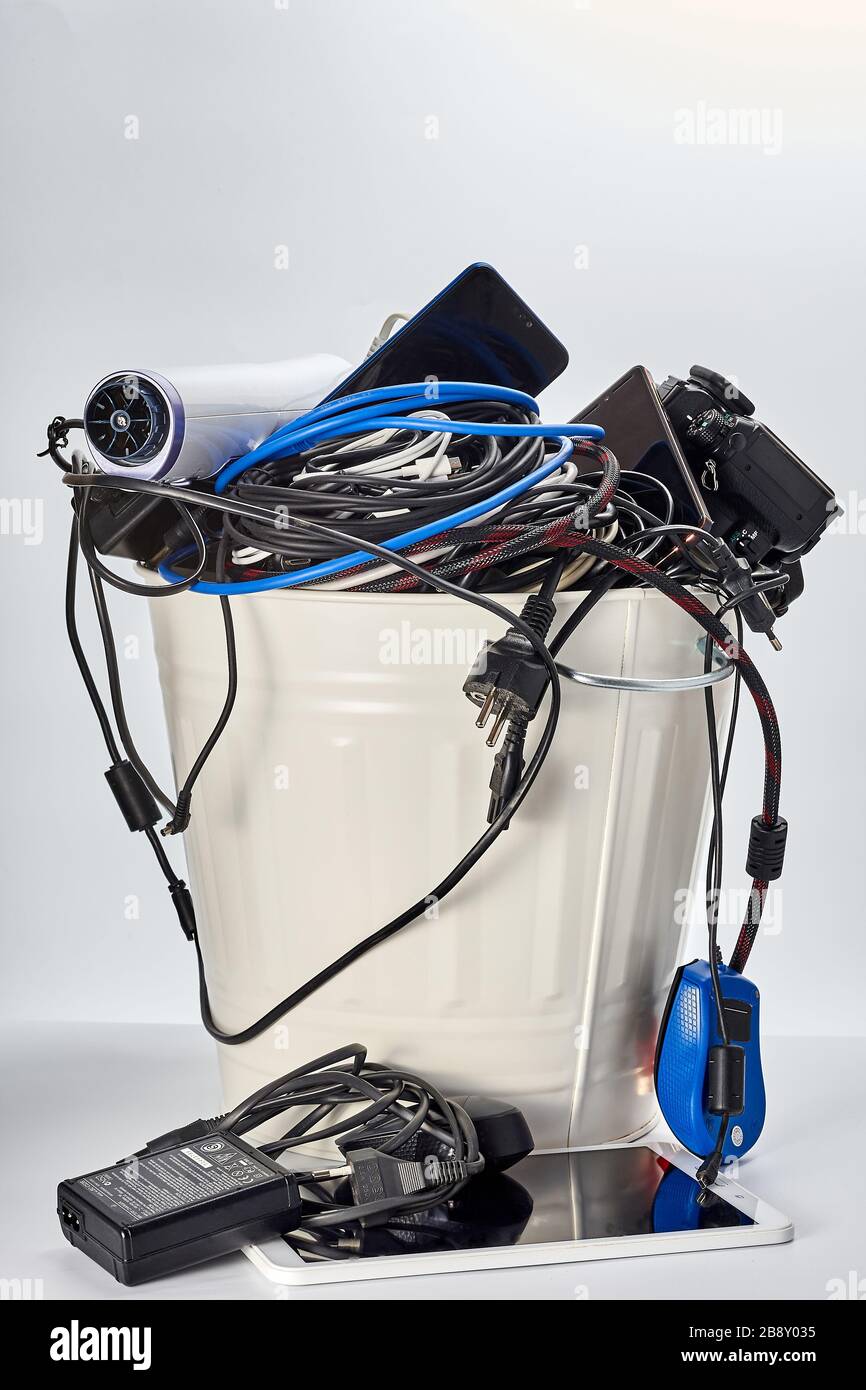 trash can filled with used obsolete electronics, wires, mobile phones, tablet, camera, electrical appliances Stock Photo