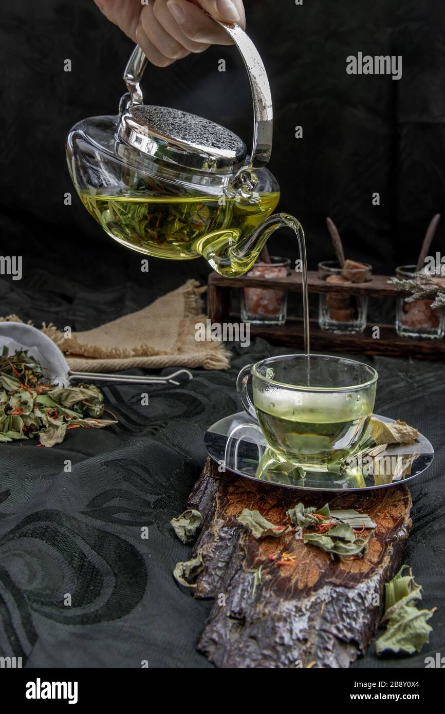 A Hot pandan leaf tea with indian marsh fleabane plant leaves and Safflower dried (Saffron substitute) is poured from the glass teapot into a glass wi Stock Photo