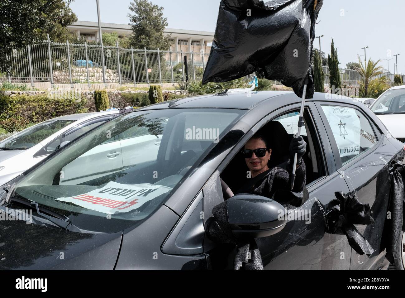 Jerusalem, Israel. 23rd Mar, 2020. The Black Flags Movement brings a convoy of over 1,000 cars to the Knesset, the Israeli Parliament, waving Israeli and black flags, protesting the Netanyahu government's alleged attempt to manipulate legislation and abuse Coronavirus emergency measures in an attempt to ‘hijack' democracy for political and personal benefits. A Supreme Court appeal is now underway aiming to restore the full powers of Parliament, blocked from functioning by Knesset Speaker, Edelstein, a Netanyahu ally. Credit: Nir Alon/Alamy Live News Stock Photo