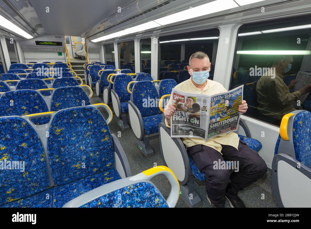 23 March, 2020: A lone man on an empty train reads Coronavirus news reports from the Daily Telegraph newspaper in Sydney, Australia, as the population abandons public places in anticipation of a city-wide lockdown. From midday today, many businesses and gathering places classified by the government as non-essential - such as pubs, restaurants, beaches, and even places of worship - have been deemed off-limits until further notice. Credit: Robert Wallace / Wallace Media Network / Alamy Live News. Stock Photo