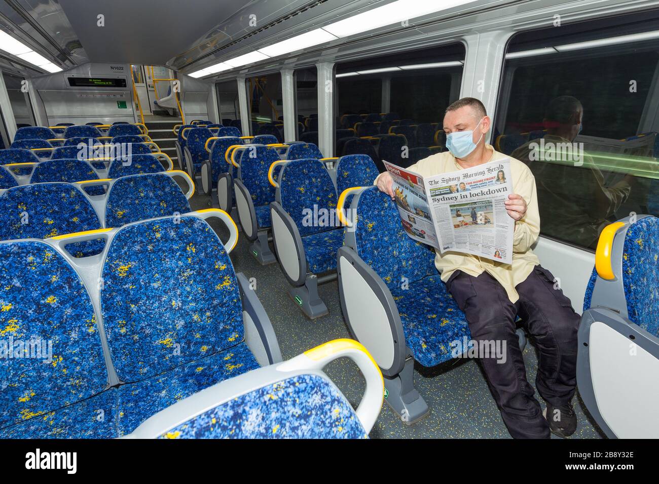 23 March, 2020: A lone man on an empty train reads Coronavirus news reports from the Sydney Morning Herald newspaper in Sydney, Australia, as the population abandons public places in anticipation of a city-wide lockdown. From midday today, many businesses and gathering places classified by the government as non-essential - such as pubs, restaurants, beaches, and even places of worship - have been deemed off-limits until further notice. Credit: Robert Wallace / Wallace Media Network / Alamy Live News. Stock Photo