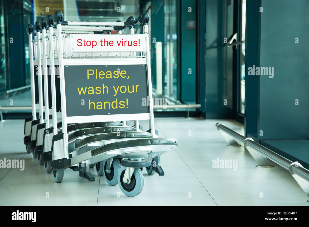 wash your hands sign on stacked airport trolleys at entrance Stock Photo