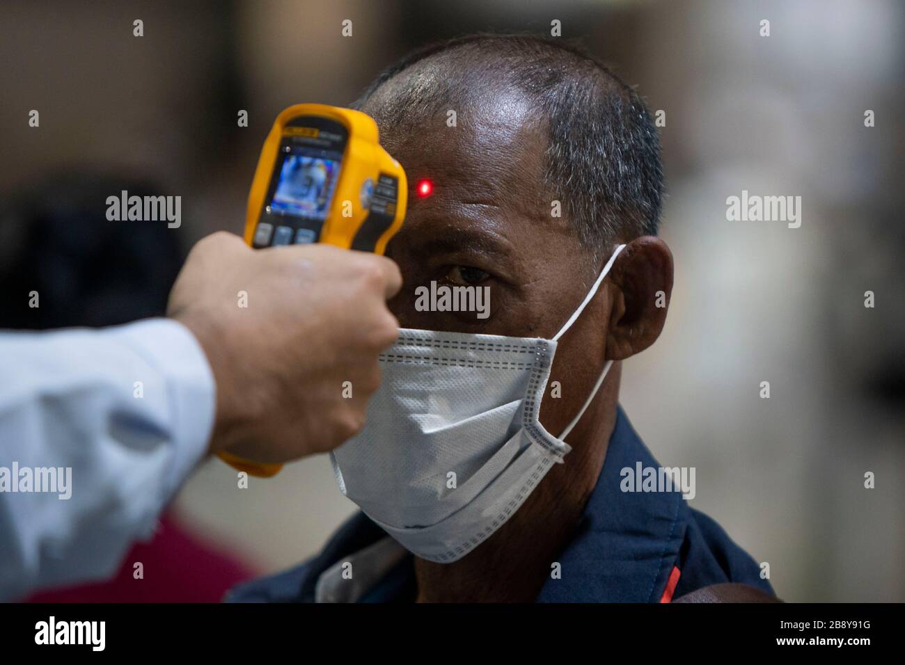 Bangkok, Bangkok, Thailand. 23rd Mar, 2020. A member of the public undergoes a temperature check before entering Bangkok's Mochit bus terminal. The travel hub was filled with thousands of travelers heading back to their home provinces after the city government ordered the mandatory closure of many nonessential businesses on March 22nd, 2020 in an effort to slow the spread of the Covid-19 virus. Large portions of the capital's workforce live paycheck to pay check, making staying in the city financially impossible due to their sudden lack of employment. Credit: ZUMA Press, Inc./Alamy Live News Stock Photo