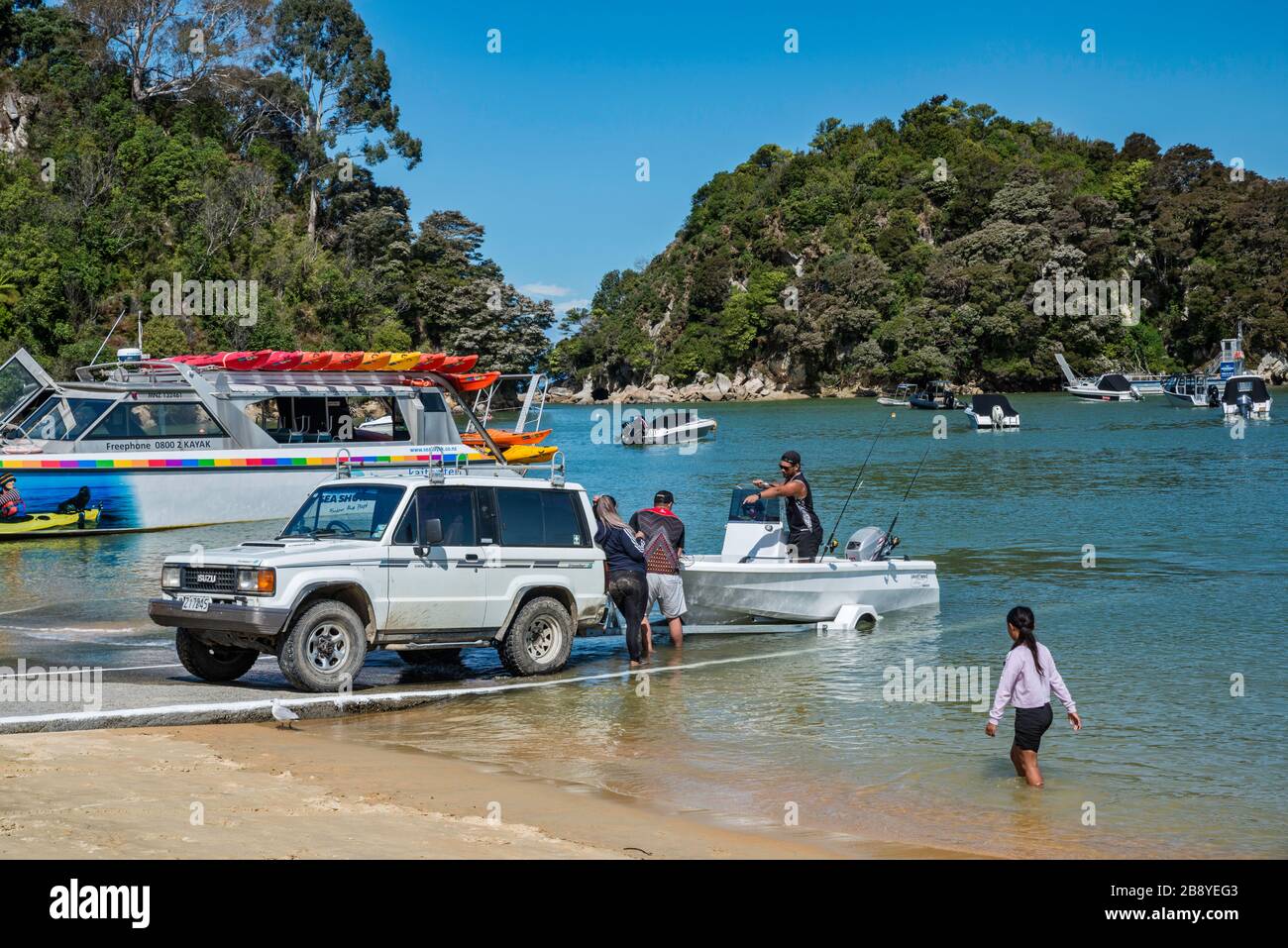 Kaka Ramp Vehicle pulling out boat at ramp, Kaiteriteri Beach over Tasman Bay ...