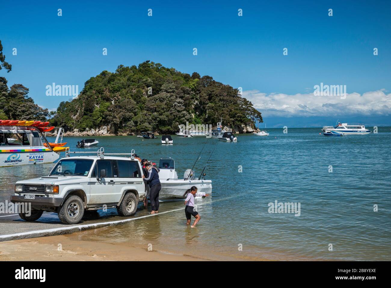 Kaka Ramp Vehicle pulling out boat at ramp, Kaiteriteri Beach over Tasman Bay ...